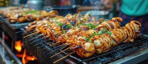 Asian street food in Bangkok with grilled squids on charcoal stoves.