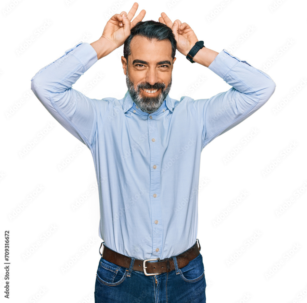 Middle aged man with beard wearing business shirt posing funny and crazy with fingers on head as bunny ears, smiling cheerful Middle aged man with beard wearing business shirt posing funny and crazy with fingers on head as bunny ears, smiling cheerful