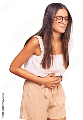 Young hispanic woman wearing casual clothes and glasses with hand on stomach because indigestion, painful illness feeling unwell. ache concept.
