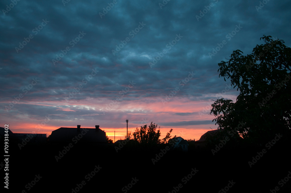 Abstract colorful background. Beautiful red sunset over a small town. Dramatic sunset sky with clouds.
