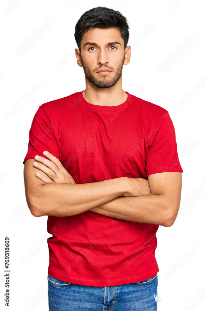 Young handsome man wearing casual red tshirt skeptic and nervous, disapproving expression on face with crossed arms. negative person. Young handsome man wearing casual red tshirt skeptic and nervous, disapproving expression on face with crossed arms. negative person.
