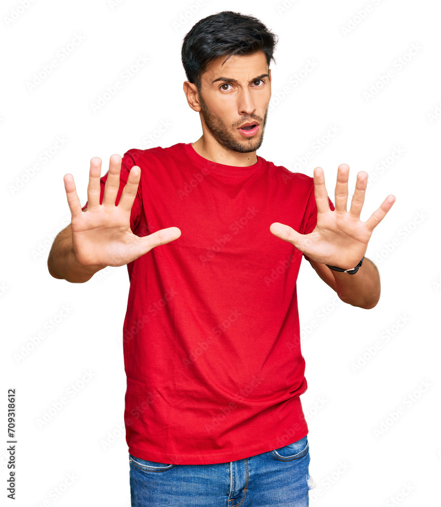 Fototapeta premium Young handsome man wearing casual red tshirt doing stop gesture with hands palms, angry and frustration expression