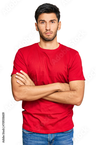 Young handsome man wearing casual red tshirt skeptic and nervous, disapproving expression on face with crossed arms. negative person.