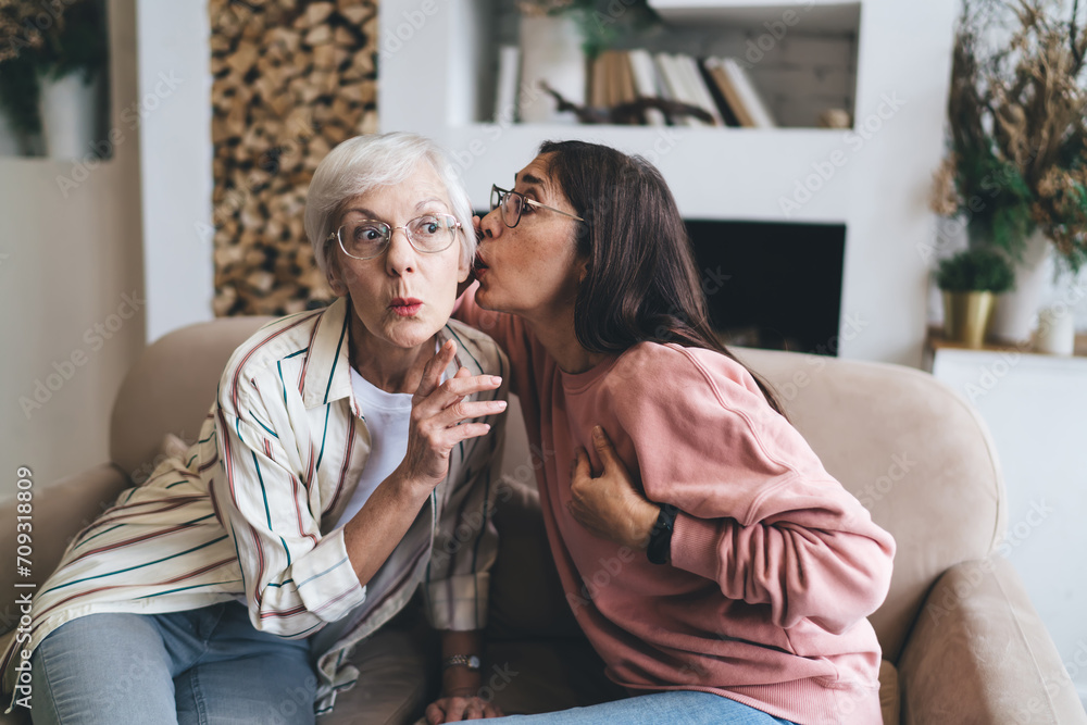 Aged multiethnic women whispering shocking rumors