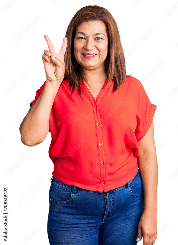 Middle age latin woman wearing casual clothes smiling with happy face winking at the camera doing victory sign. number two. Middle age latin woman wearing casual clothes smiling with happy face winking at the camera doing victory sign. number two.