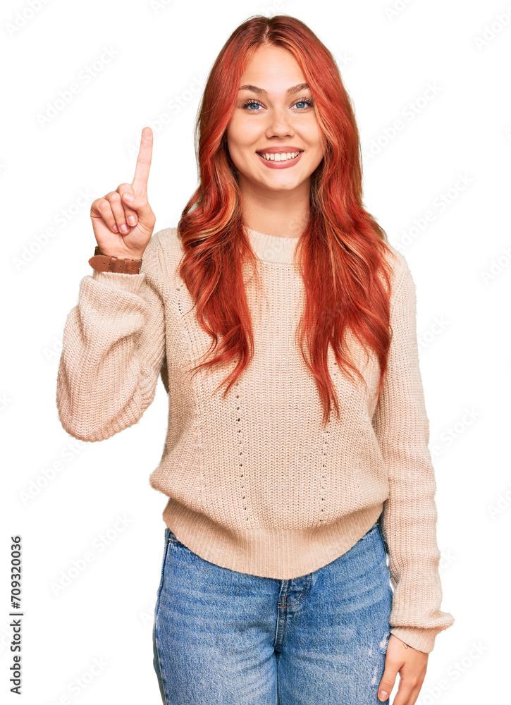 Young redhead woman wearing casual winter sweater showing and pointing up with finger number one while smiling confident and happy. Young redhead woman wearing casual winter sweater showing and pointing up with finger number one while smiling confident and happy.