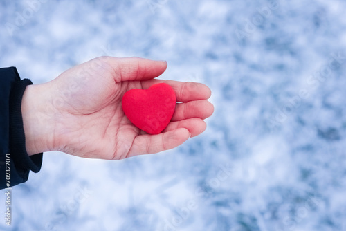 A In the hands of the heart in winter on the road in the park travel background