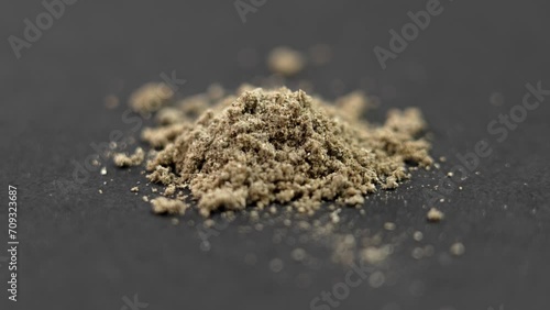 Dried medicinal herb powder from supplement pill on a black background close up. Alternative herbal medicine concept. Rotation. Macro shot