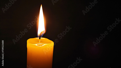 Yellow candle, light burning in the dark, candle lit in a dark environment symbolizing faith or hope