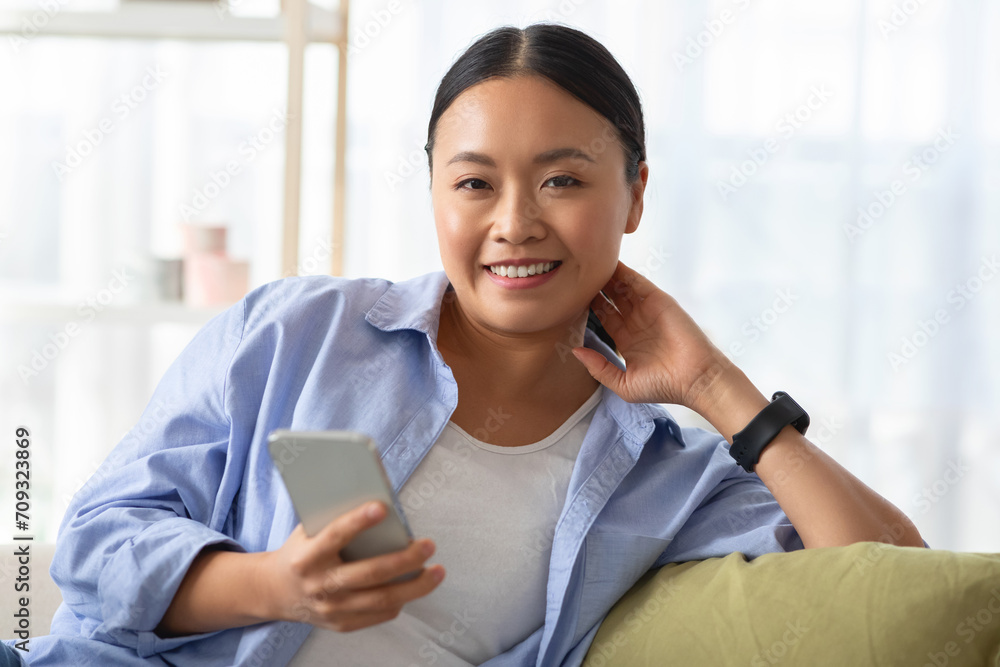 Pretty young korean woman chilling on couch, using phone Pretty young korean woman chilling on couch, using phone
