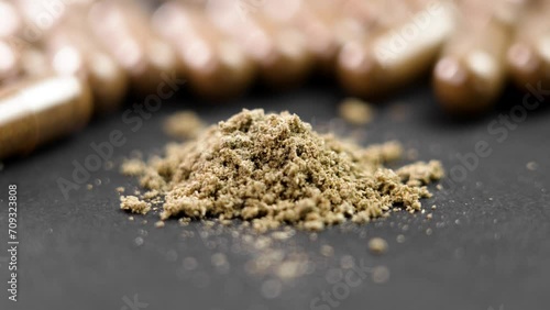 Supplement brown plant capsules and powder on black surface. Herbal medicinal product. Rotation. Macro shot photo