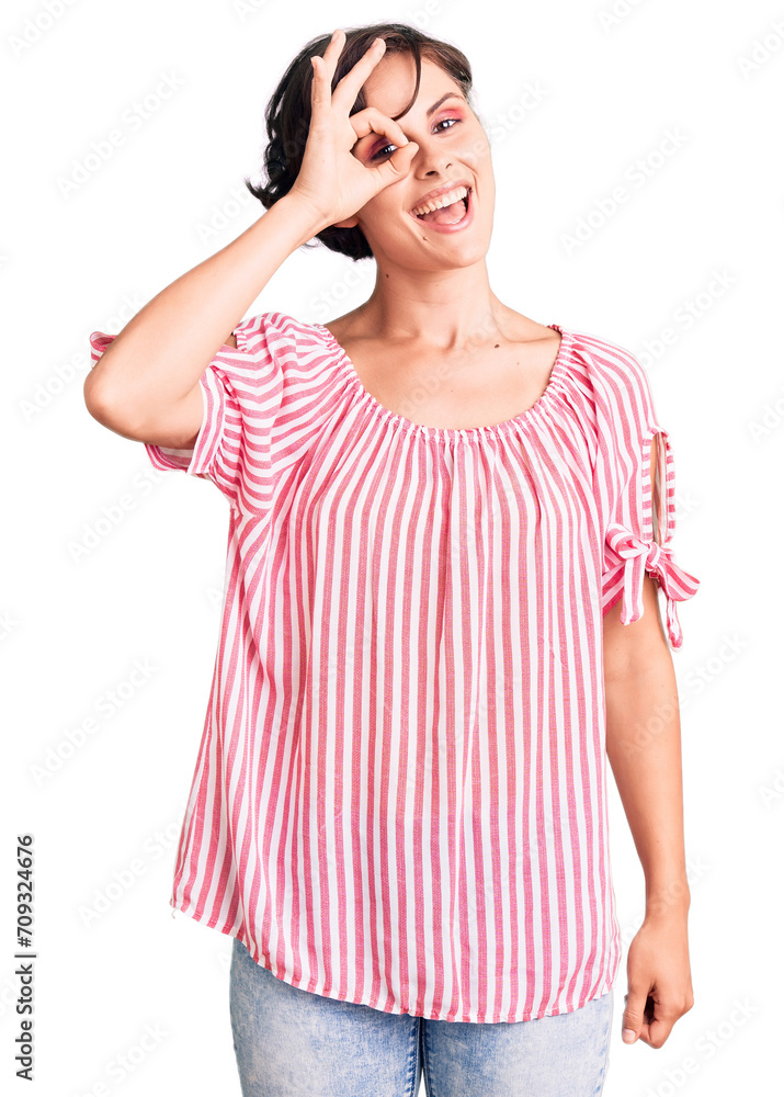 Beautiful young woman with short hair wearing casual summer clothes doing ok gesture with hand smiling, eye looking through fingers with happy face. Beautiful young woman with short hair wearing casual summer clothes doing ok gesture with hand smiling, eye looking through fingers with happy face.