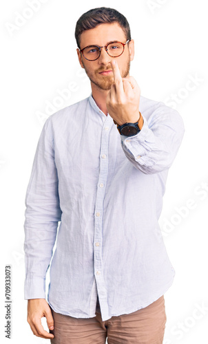 Handsome young man with bear wearing elegant business shirt and glasses showing middle finger, impolite and rude fuck off expression