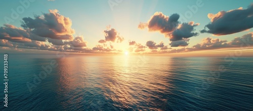 Simplistic aerial ocean sunset view with sky, clouds, and serene water.