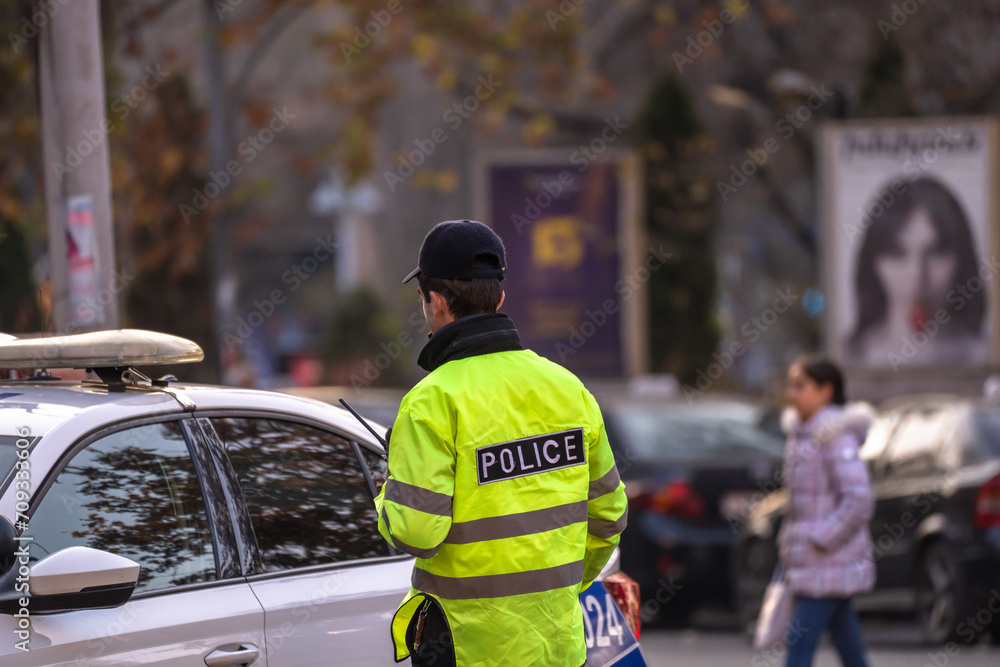 Fototapeta premium A policeman next to a police car in the city