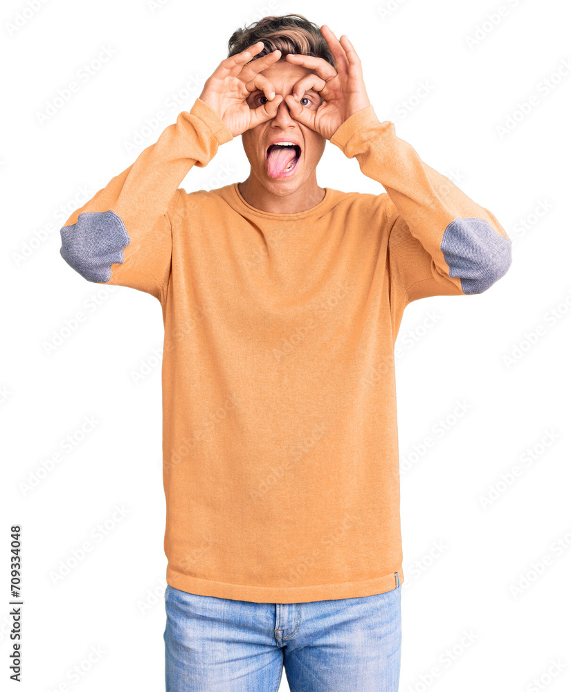 Young handsome man wearing casual clothes doing ok gesture like binoculars sticking tongue out, eyes looking through fingers. crazy expression.