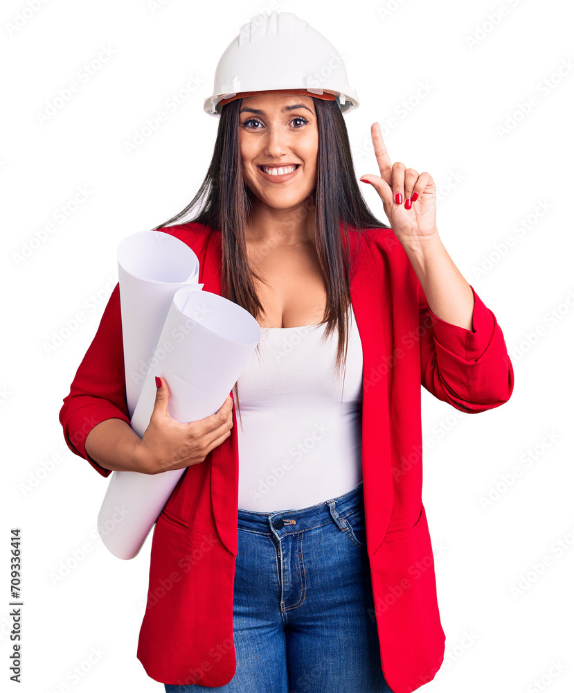 Young beautiful brunette woman wearing hardhat holding architect blueprint surprised with an idea or question pointing finger with happy face, number one Young beautiful brunette woman wearing hardhat holding architect blueprint surprised with an idea or question pointing finger with happy face, number one