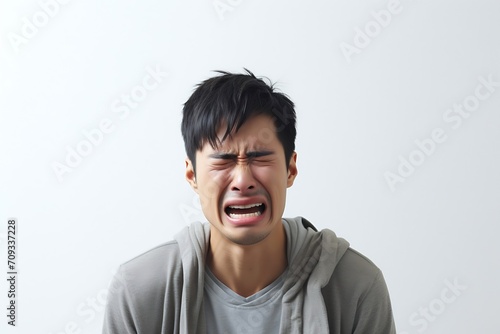 Generative AI : portrait of desperate very emotional crying asian man on white studio background photo
