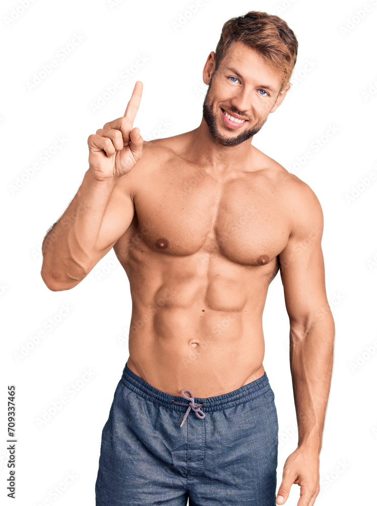 Fototapeta premium Young caucasian man standing shirtless showing and pointing up with finger number one while smiling confident and happy.