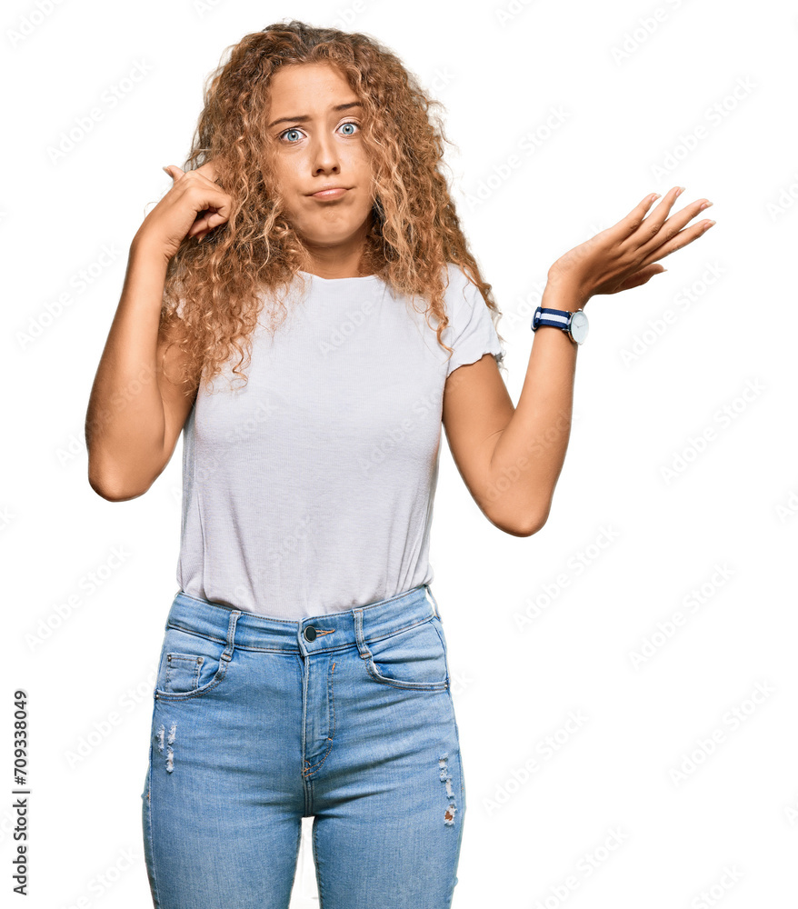 Beautiful caucasian teenager girl wearing casual white tshirt confused and annoyed with open palm showing copy space and pointing finger to forehead. think about it. Beautiful caucasian teenager girl wearing casual white tshirt confused and annoyed with open palm showing copy space and pointing finger to forehead. think about it.