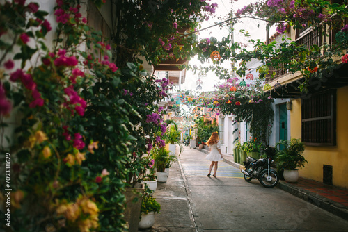 Colorful street with flowers and a strolling woman in Cartagena, Colombia photo