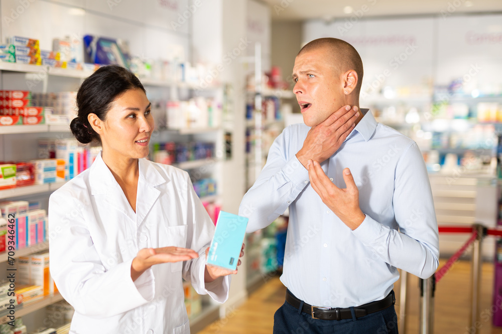 Man complains to a female pharmacist about a sore throat. Help in choosing a medicine in a pharmacy
