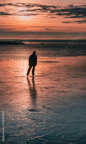 silhouette of a person iceskating on a frozen lake