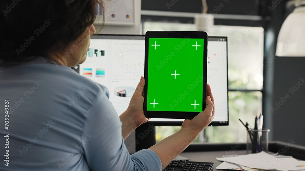 Office worker examines greenscreen layout in coworking space, working on business operations and looking at isolated chromakey display. Woman holding tablet with blank copyspace. Office worker examines greenscreen layout in coworking space, working on business operations and looking at isolated chromakey display. Woman holding tablet with blank copyspace.