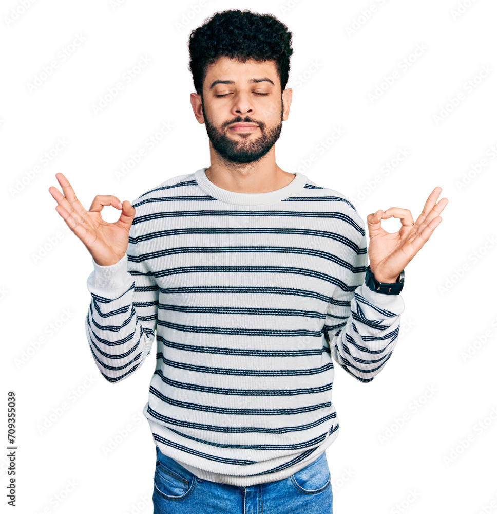 Young arab man with beard wearing casual striped sweater relaxed and smiling with eyes closed doing meditation gesture with fingers. yoga concept. Young arab man with beard wearing casual striped sweater relaxed and smiling with eyes closed doing meditation gesture with fingers. yoga concept.