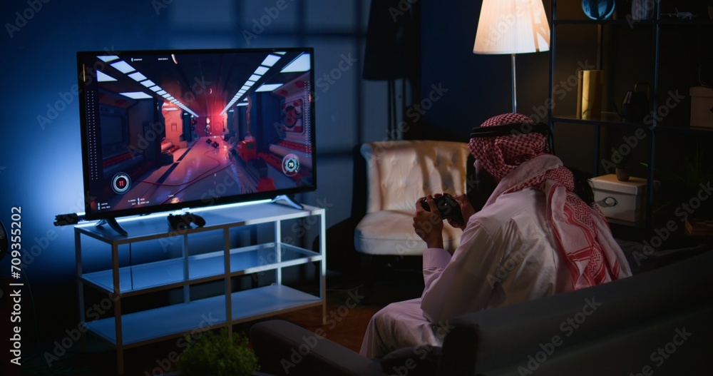 Arab gamer feeling gutted after losing singleplayer action videogame level, being outsmarted by enemies. Upset man placing hands on head in frustration after seeing game over screen