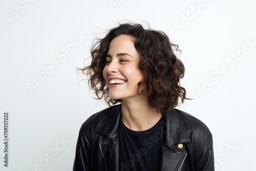 Portrait of a young woman with curly hair laughing against a white background