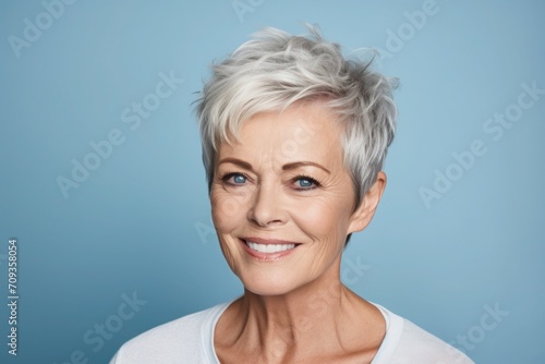 A poised and relaxed portrait of a mature woman in a light blue setting with attractive silver short haircut, Women´s and Mother´s day