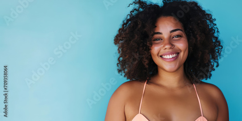 Portrait of a radiant plus-size woman in stylish swimwear against a flat blue background with copy space, banner template, celebrating body positivity. Confident Plus-Size Model portrait in Swimwear. photo