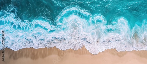 Ocean water viewed from above with clear foam. Sand visible beneath. Beach, summer, vacation, coastline, seashore, travel, tourism, wallpaper.