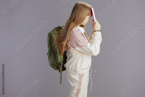 stressed modern teenager girl in beige tracksuit with backpack