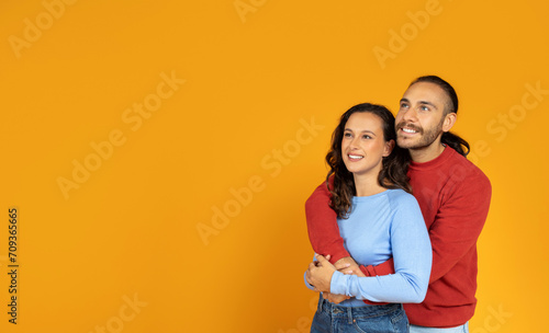 Beautiful young european couple hugging and looking at copy space © Prostock-studio