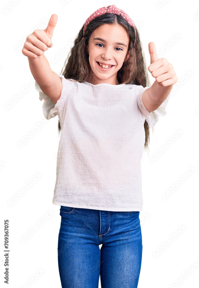 Cute hispanic child girl wearing casual white tshirt approving doing positive gesture with hand, thumbs up smiling and happy for success. winner gesture. Cute hispanic child girl wearing casual white tshirt approving doing positive gesture with hand, thumbs up smiling and happy for success. winner gesture.