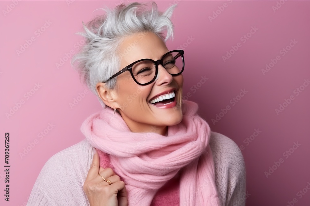 Portrait of a happy senior woman in glasses and scarf over pink background Portrait of a happy senior woman in glasses and scarf over pink background