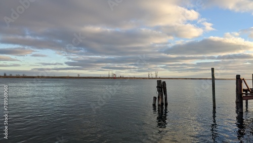 Decaying dock wood in slowly moving water, with large clouds overhead. Taken on Harsen's Island, located to the northeast of Detroit along the St Clair River.