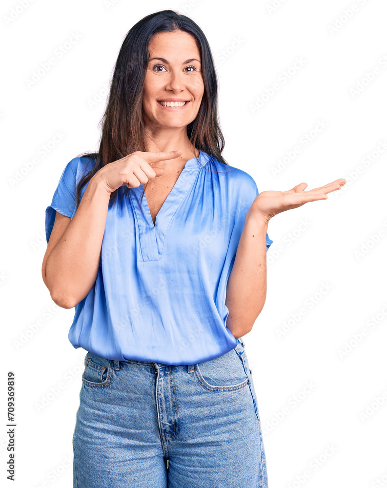 Young beautiful brunette woman wearing casual t-shirt amazed and smiling to the camera while presenting with hand and pointing with finger. Young beautiful brunette woman wearing casual t-shirt amazed and smiling to the camera while presenting with hand and pointing with finger.