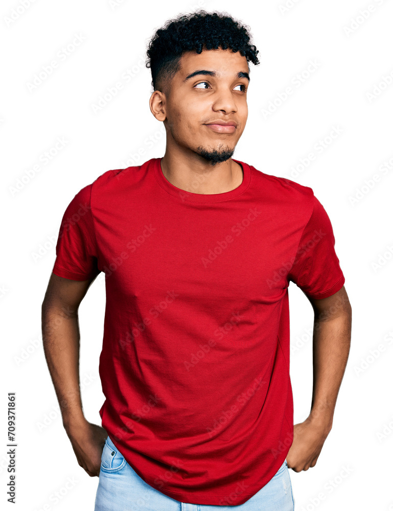 Fototapeta premium Young african american man wearing casual red t shirt smiling looking to the side and staring away thinking.