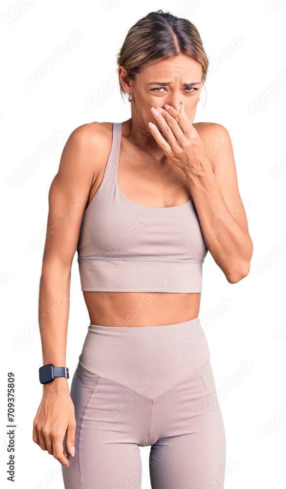 Beautiful caucasian woman wearing sportswear smelling something stinky and disgusting, intolerable smell, holding breath with fingers on nose. bad smell Beautiful caucasian woman wearing sportswear smelling something stinky and disgusting, intolerable smell, holding breath with fingers on nose. bad smell