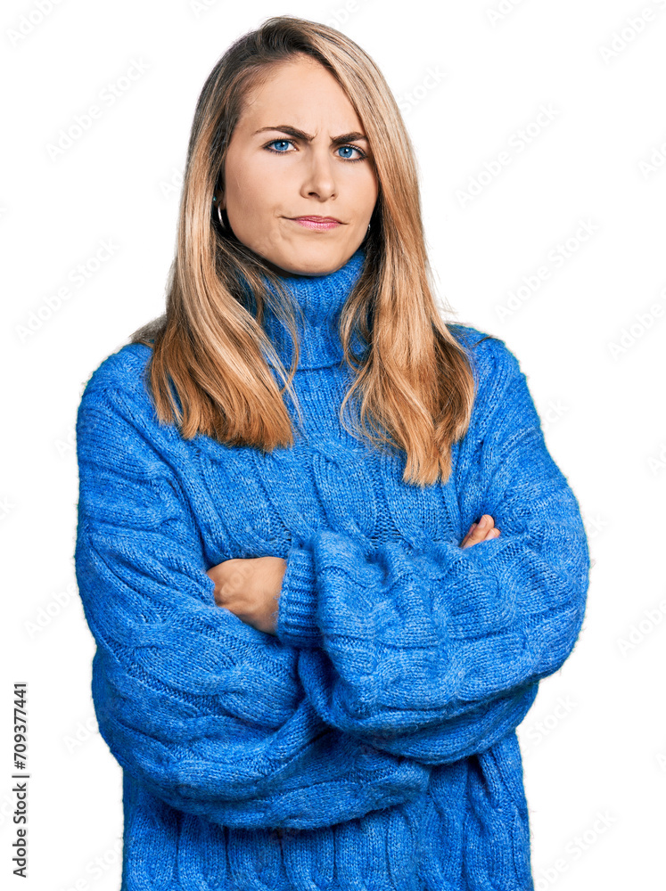 Young blonde woman wearing casual sweater skeptic and nervous, disapproving expression on face with crossed arms. negative person.