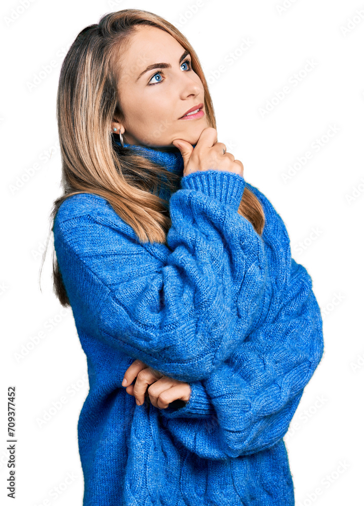 Young blonde woman wearing casual sweater with hand on chin thinking about question, pensive expression. smiling with thoughtful face. doubt concept. Young blonde woman wearing casual sweater with hand on chin thinking about question, pensive expression. smiling with thoughtful face. doubt concept.