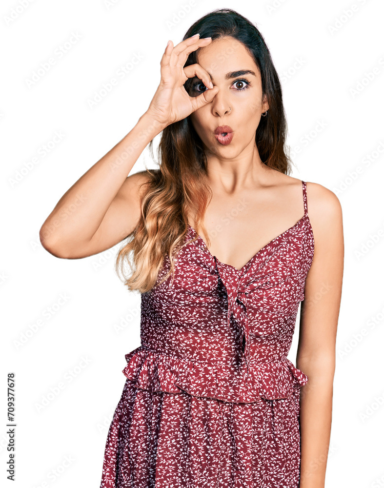 Beautiful hispanic woman wearing summer dress doing ok gesture shocked with surprised face, eye looking through fingers. unbelieving expression. Beautiful hispanic woman wearing summer dress doing ok gesture shocked with surprised face, eye looking through fingers. unbelieving expression.