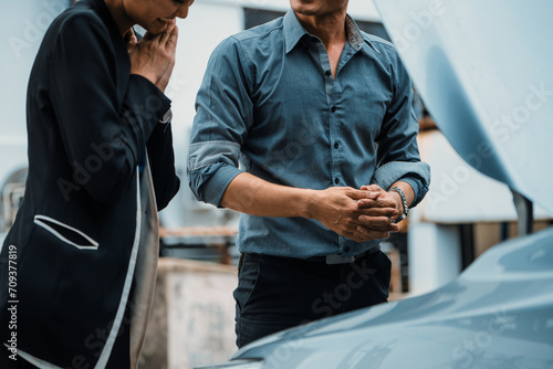Man help woman fix the car problem. He pop up the car hood to repair the damaged part. uds photo