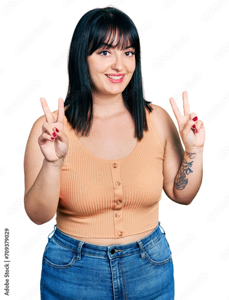 Young hispanic plus size woman wearing casual clothes smiling looking to the camera showing fingers doing victory sign. number two. Young hispanic plus size woman wearing casual clothes smiling looking to the camera showing fingers doing victory sign. number two.