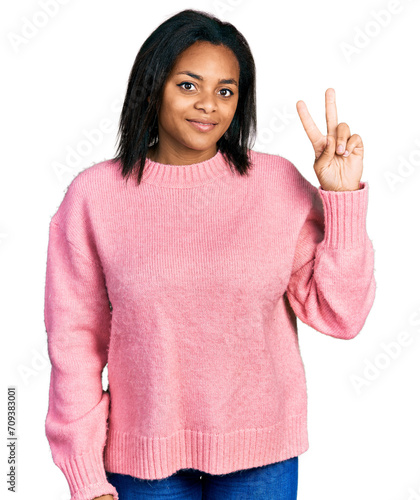 Beautiful hispanic woman wearing casual winter sweater smiling looking to the camera showing fingers doing victory sign. number two.