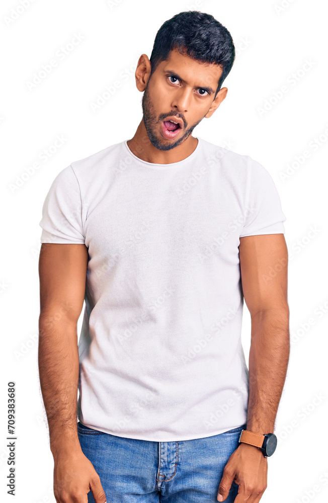Young latin man wearing casual clothes in shock face, looking skeptical and sarcastic, surprised with open mouth Young latin man wearing casual clothes in shock face, looking skeptical and sarcastic, surprised with open mouth