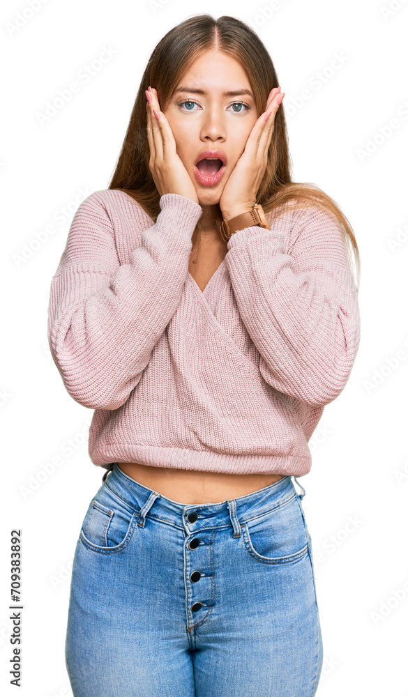 Beautiful blonde woman wearing casual winter pink sweater afraid and shocked, surprise and amazed expression with hands on face Beautiful blonde woman wearing casual winter pink sweater afraid and shocked, surprise and amazed expression with hands on face